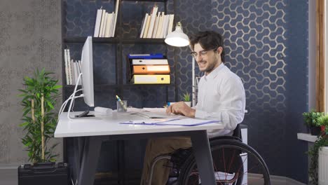 Disabled-businessman-sitting-in-wheelchair-rejoicing-and-working-in-office.